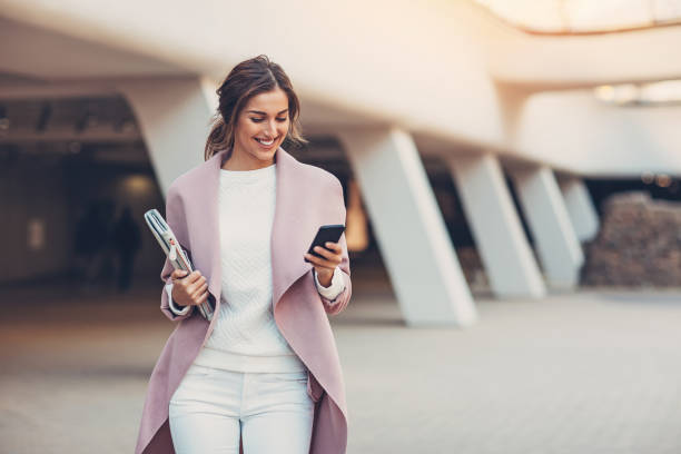 Woman in stylish attire holding a magazine and smartphone, embodying the future of smart clothing.